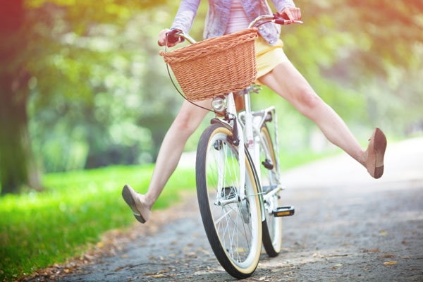 Woman riding bicycle with her legs in the air